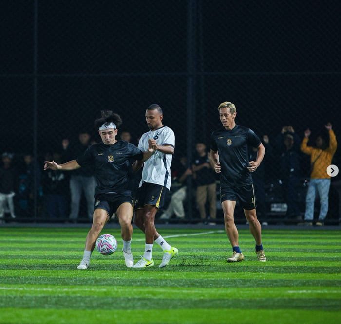 Players contesting the ball on a floodlit pitch