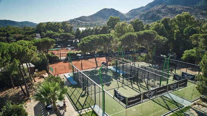 Outdoor clay tennis and padel courts among pine trees